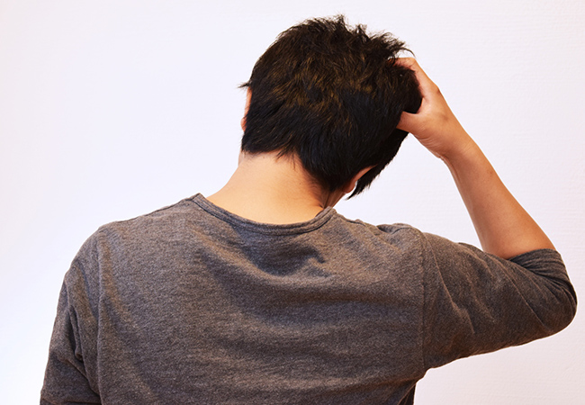 頭を右側に傾けて手をあてる男性